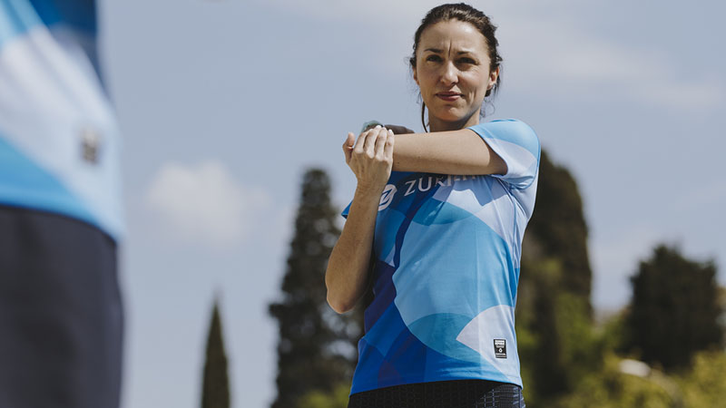 chica, con camiseta de deporte Zurich, estirando los brazos
