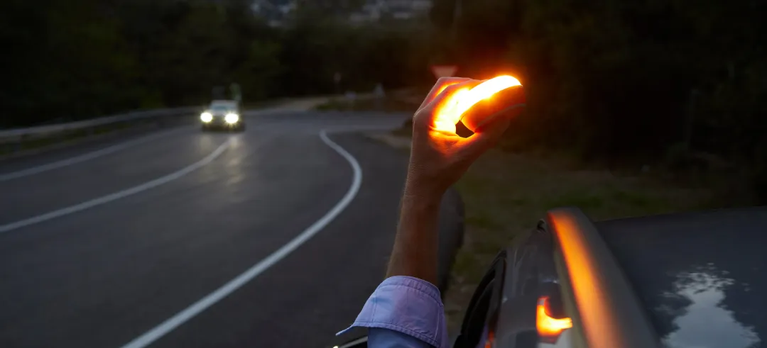 Persona desde el coche colocando una baliza en la parte superior de un coche