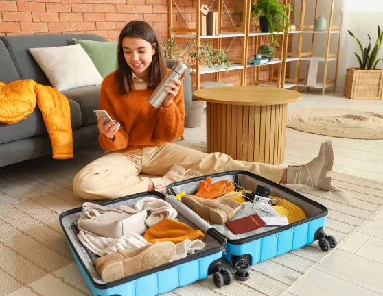 Mujer haciendo la maleta sentada en el suelo del salón