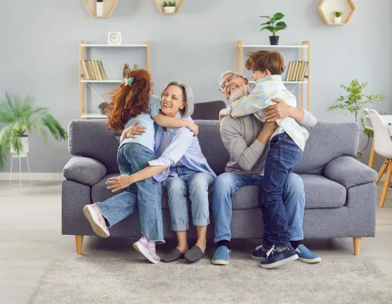 Nietos abrazando a los abuelos sentados en el sofá de la casa