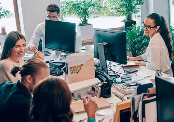 Diferentes trabajadores en una oficina con ordenadores en sus puestos